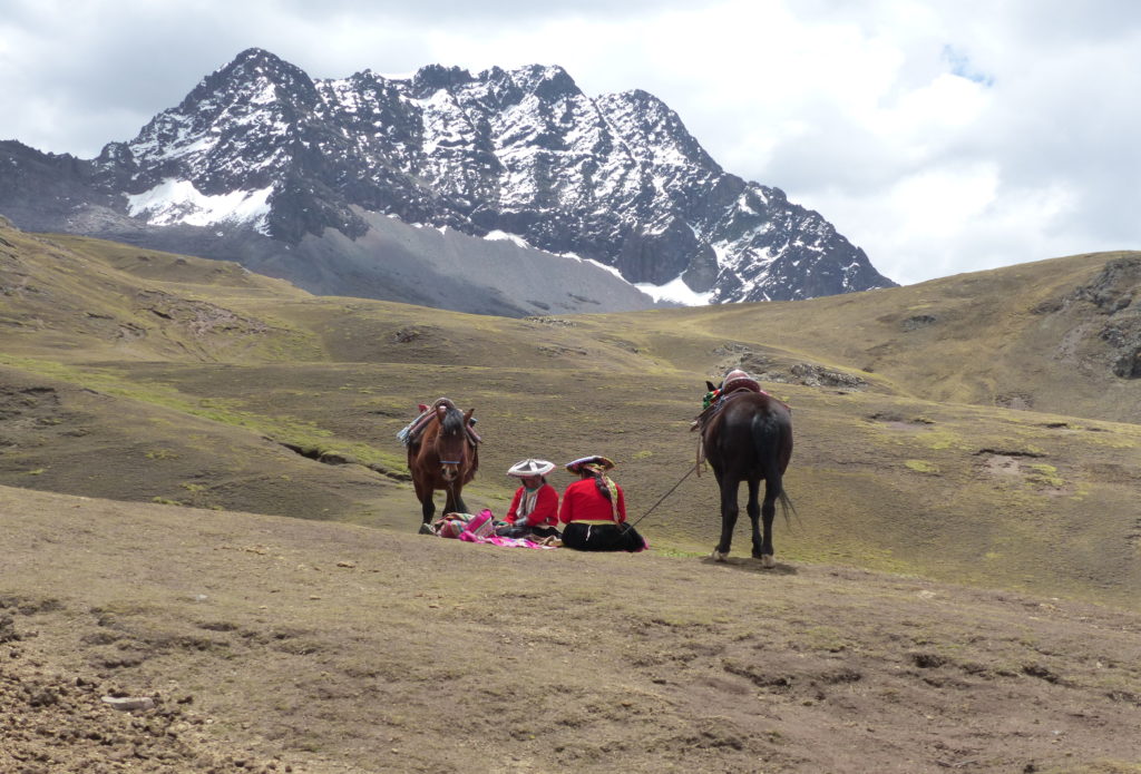 Zwei personen in traditioneller Kleidung mit zwei Pferden in den Bergen