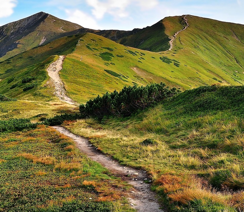 Mit Gras überwachsende Berge mit einem Wanderweg