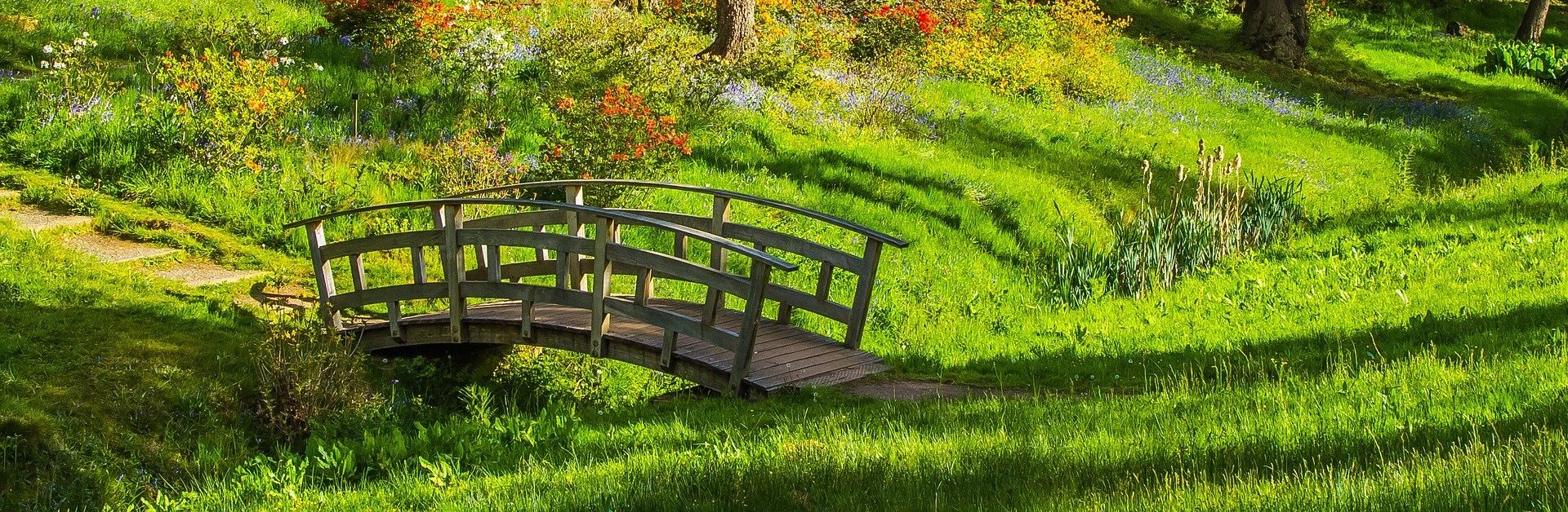 Eine Brücke führt über einen Graben in einem schönen grünen Garten.