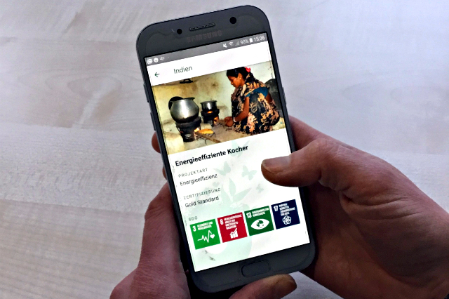 Hände, die ein Smartphone mit der Klima-Kollekte-App zeigen